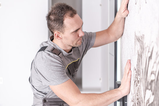 Caucasian Men Installing Wallpaper on His Bedroom's Wall