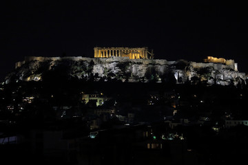 The ancient hilltop Acropolis of Athens, Greece is shown illuminated at night, with the Parthenon featured in the center.