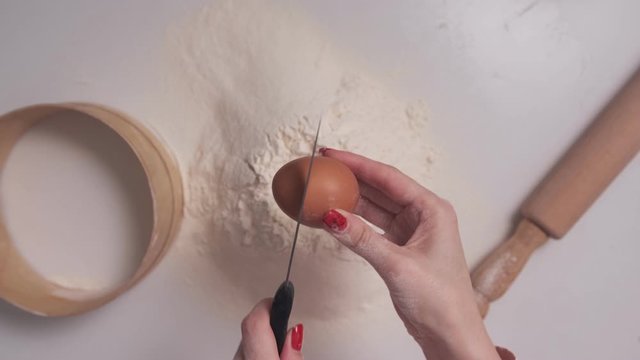 Women's Hands Break An Egg Into Flour For Making Dough, Top View, POV.