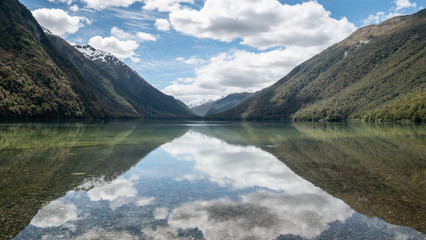 Beautiful still reflections on a lake during sunny day. Symmetric photo taken at lake Gunn, Fiordland National Park, New Zealand