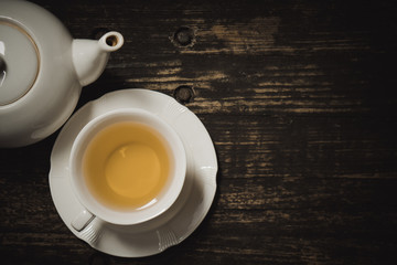 Delicious organic healthy herbal yellow hot tea set drink with clean white ceramic classic cup & pot on old vintage natural wooden table authentic homemade exotic high tea afternoon set serve in cafe