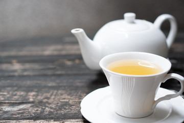 Delicious organic healthy herbal yellow hot tea set drink with clean white ceramic classic cup & pot on old vintage natural wooden table authentic homemade exotic high tea afternoon set serve in cafe