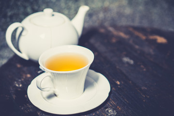 Delicious organic healthy herbal yellow hot tea set drink with clean white ceramic classic cup & pot on old vintage natural wooden table authentic homemade exotic high tea afternoon set serve in cafe