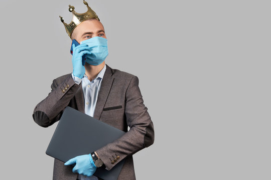 Young businessman in a crown and a protective face mask and gloves. Stay home during quarantine of coronavirus Covid-19. Empty space for text.