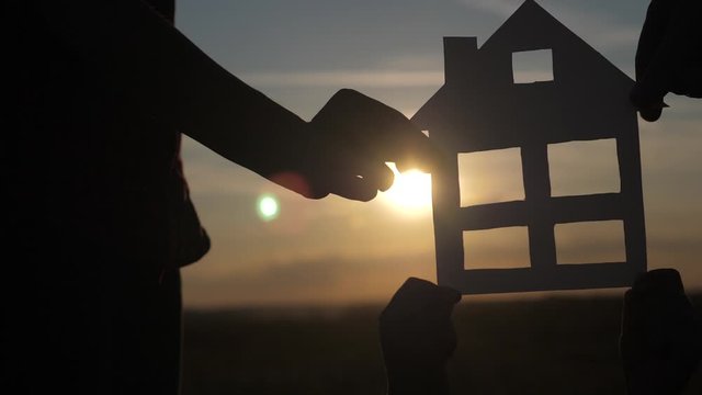 happy family construction house teamwork concept. Mom daddy and son holding home a paper house in his hands at sunset silhouette sunlight. life symbol ecology video lifestyl . boy and girl,man hold