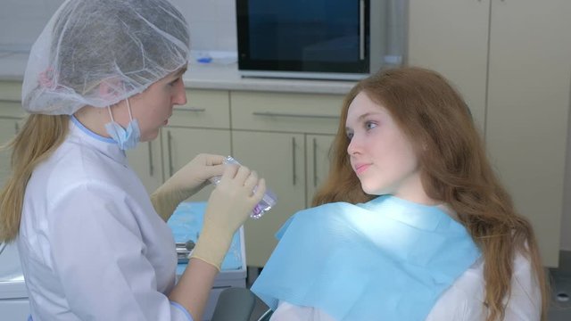 Orthodontist doctor explains young woman how to care about silicone invisible transparent braces in dentistry. Portrait of teen girl. Correcting teeth. Oral hygiene and treatment, cure in dentistry.