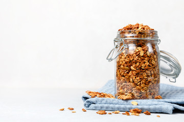 Oatmeal granola cereal in open glass jar on white background