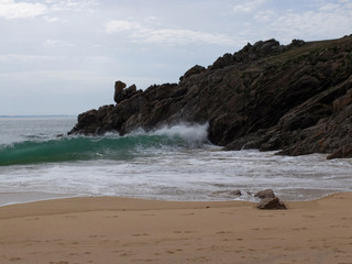 Une plage de sables fin avec la côte rocheuse surplombant la mer