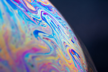 Abstract sphere part multi-colored on a black background. Soap bubble overflowing. Abstraction similar to the surface of the planet