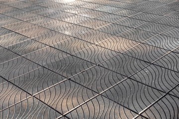 old gray square tiles on the floor, with a wavy pattern on a blurred background. rough surface texture