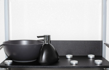 one black bowl and one black porcelain dispenser on a black shelf
