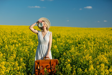Fototapeta premium woman in dress with suitcase and alarm clock in rapeseed field