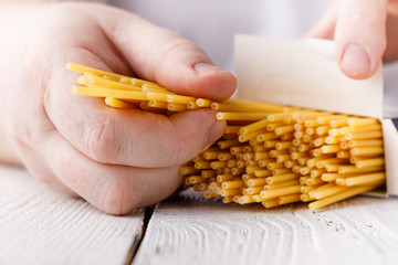 Man hands in the kitchen holding spaghetti