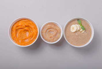 Bowls with healthy baby food on color background. Purees, made of fresh organic fruit and vegetables, flay lay, top view, concept. Kids meal