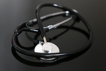 Stethoscope on dark glass table. Concept of diagnosis and health care