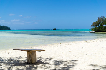 isolated wooden table on a paradisiac beach. sky is blue and water aquamarine