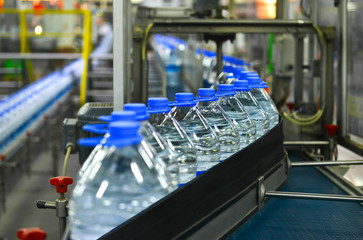 Mass production water bottles in factory. Pet bottles on the marching band.