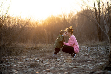 Beautiful mother playing with her son in nature against sunset. Mother's day concept
