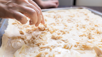 Woman spreading chunks of meat cooking pizza home