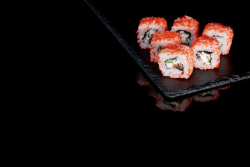 Philadelphia roll with salmon, cheese and cucumber on a black background with reflection. Sushi Philadelphia