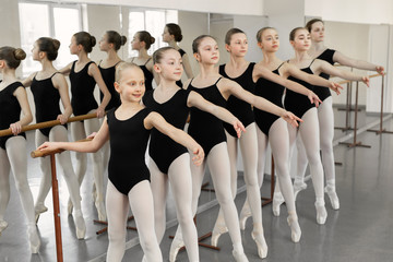 Ballet background, young ballerinas training. Female dancers legs in pointe shoes, making exercises. Classical dance school