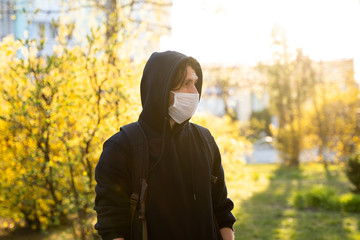 Man in black hoodie wearing a medical mask to prevent germs, toxic fumes, dust. Prevention of bacterial infection Corona virus or Covid 19 epidemic on a street. Coronavirus global pandemic quarantine.