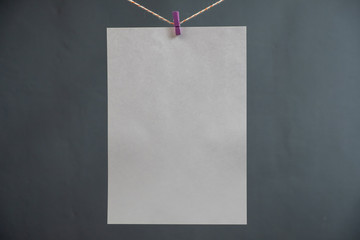 A sheet of white paper on a rope for notes on a gray background.