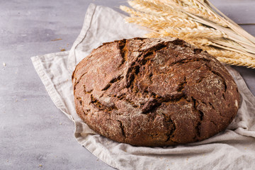 Freshly baked rye bread on cotton napkin, on grey table, space for text. Close up