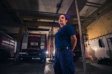 Portrait of female firefighter standing against firetruck at station