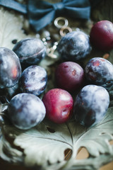 Ripe dark burgundy plums close-up on a vintage saucer