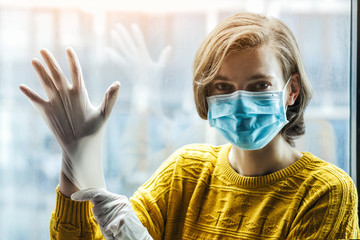 Woman in medical mask putting on gloves. Protection from catching disease or dirt. Pandemic of coronavirus concept.