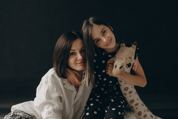 Loving mother and daughter gently hug each other, they smile and enjoy communication. A photo with a blurred background.