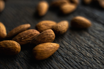 Almonds scattered on the wooden vintage table. Almond is a healthy vegetarian protein nutritious food. Almonds on rustic old wood.