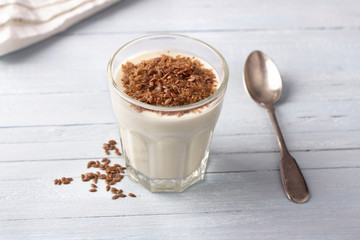 Simple healthy breakfast or snack. Natural yogurt with ground flax seeds in glasses on a light blue background