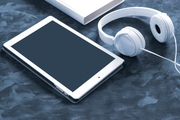 Paper book, ebook and audio book format on a black wooden table. Top down view of a desktop with empty copy space for Editor's content.	