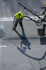 Road surface restoration work. The worker performs on road patcher work on the repair of cracks by...