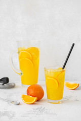 Summer refreshing cocktail with orange. Refreshing drink in a glass on a light stone background with bartender tools.