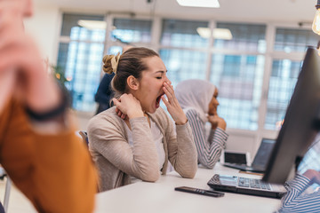 Portrait of a tired businesswoman yawning while having a business meeting in the office.