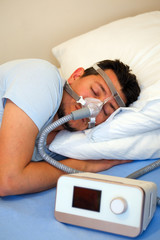 Healthy young man wearing nasal mask and using Cpap machine for sleeping smoothly all night long on...