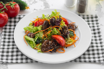 Salad of fresh vegetables, chicken liver and Korean carrots. Dressed with sauce and sprinkled with sesame seeds. Cook at home.