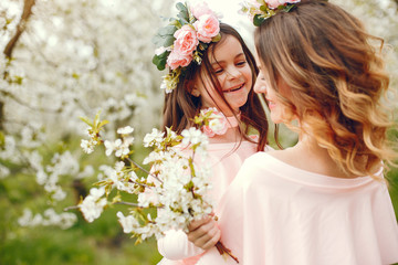 Naklejka premium Pretty mother with daughter. Family in a spring park. Woman in a pink dress. Child with a flowers