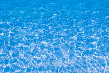 Blue clear water in the pool. Texture of water surface. Overhead view, Swimming pool bottom caustics ripple and flow with waves background.
