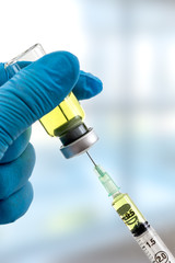 Gloved hands holding a syringe while loading a dose. Concepts of medical treatment, epidemic or vaccine on blured background