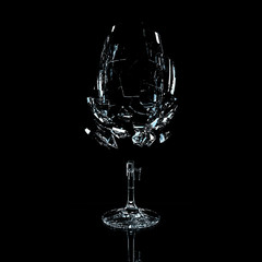 3D render of a glass on a black background. Studio lighting. Glass fragments go to smithereens