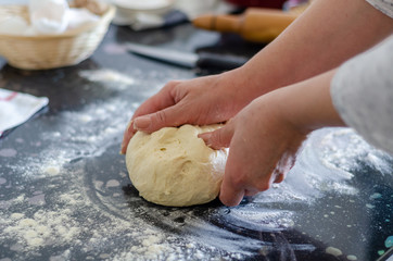 Making dough by female hands on black table background. Cooking concept.