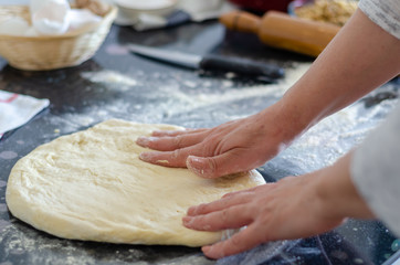 Making dough by female hands on black table background. Cooking concept.
