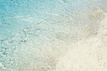 Soft waves with foam of blue ocean on the sandy beach. Background.