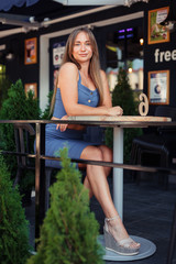 Obraz na płótnie Canvas Vertical photo of a girl in a cafe. A girl in a blue top sits sideways.