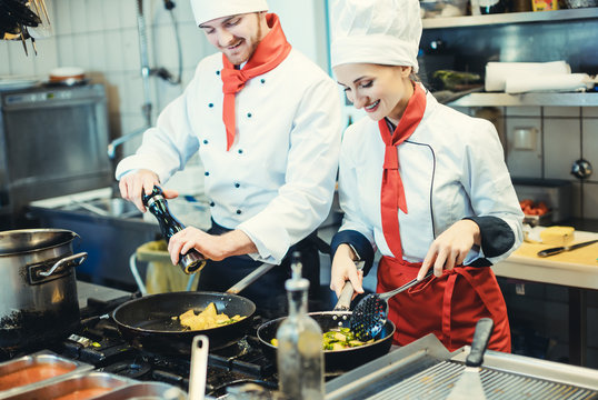 Team Of Chefs In A Kitchen Preparing Fantastic Food In Pans