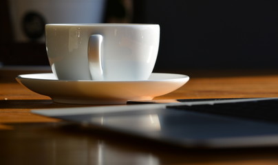 Laptop and a Cup of coffee on the table in the cafe.
